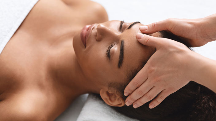 massage therapist massaging male client's temples